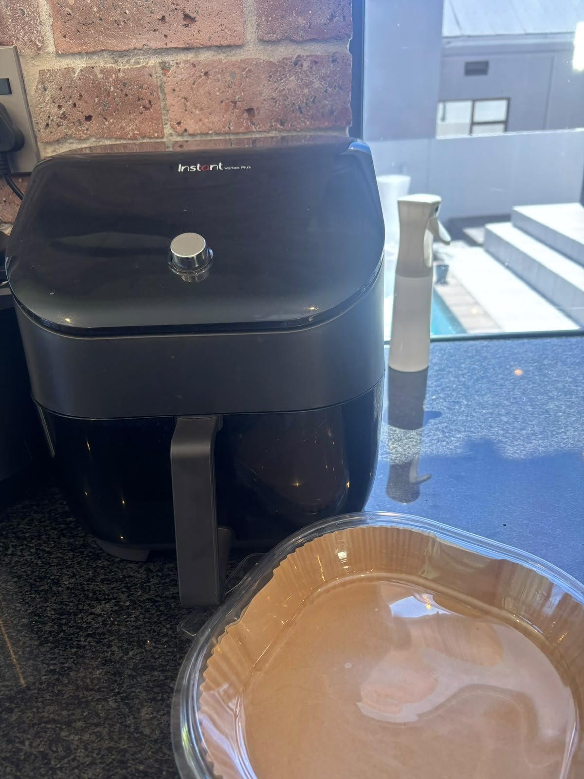 My Instant Vortex Plus air fryer with a paper liner beside it on the counter