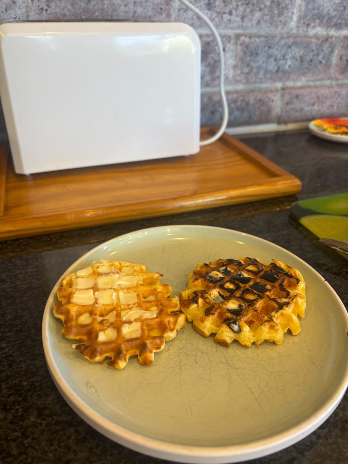 Two protein waffles on a plate, one with butter and one with butter and Bovril